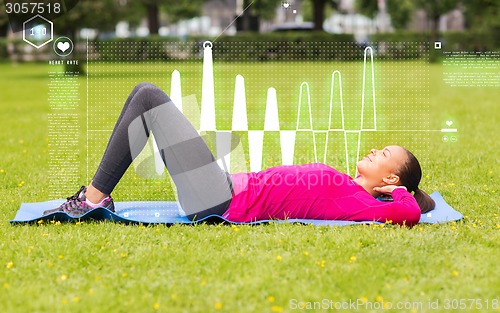 Image of smiling woman doing exercises on mat outdoors