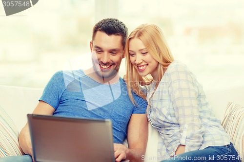 Image of smiling happy couple with laptop at home