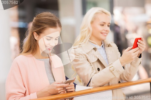 Image of happy women with smartphones and shopping bags