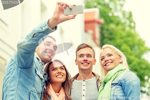 Image of group of smiling friends making selfie outdoors