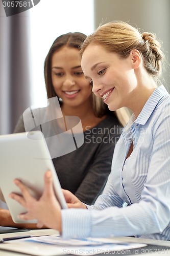 Image of smiling businesswomen with tablet pc in office