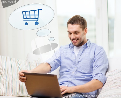 Image of smiling man with laptop shopping online at home