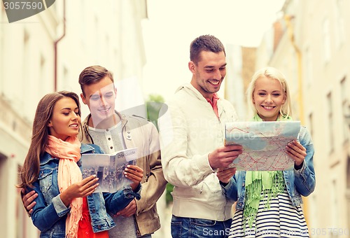 Image of group of smiling friends with city guide and map