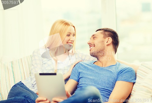 Image of smiling happy couple with tablet pc at home