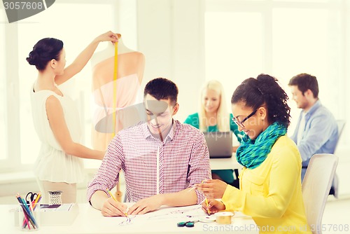 Image of smiling fashion designers working in office