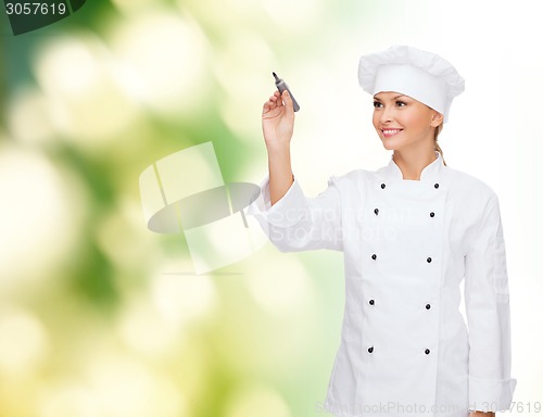 Image of smiling female chef writing something on air