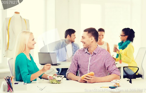 Image of smiling fashion designers having lunch at office