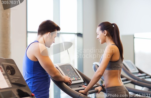 Image of happy woman with trainer on treadmill in gym