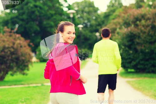 Image of smiling couple running outdoors