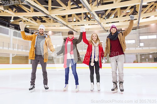 Image of happy friends waving hands on skating rink