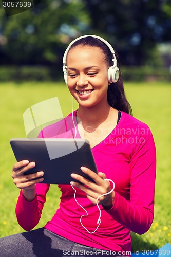 Image of smiling woman with tablet pc outdoors