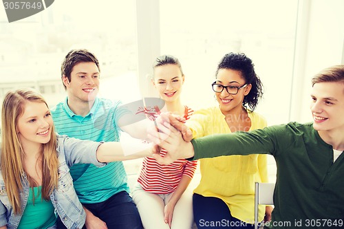 Image of smiling students making high five gesture sitting