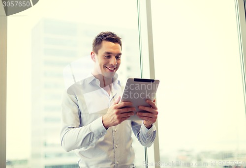 Image of smiling businessman with tablet pc in office