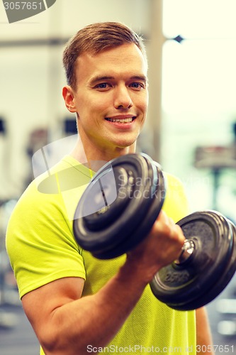 Image of smiling man with dumbbell in gym