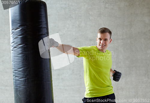 Image of young man in gloves boxing with punching bag