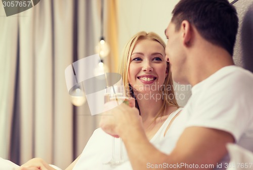 Image of smiling couple with champagne glasses in bed