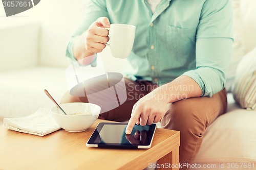 Image of close up of man with tablet pc having breakfast