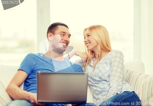 Image of smiling happy couple with laptop at home