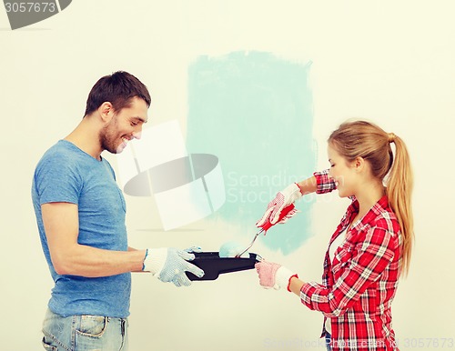 Image of smiling couple painting wall at home