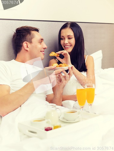 Image of smiling couple having breakfast in bed in hotel