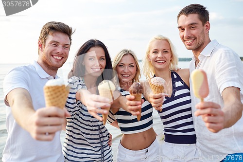 Image of smiling friends eating ice cream on beach