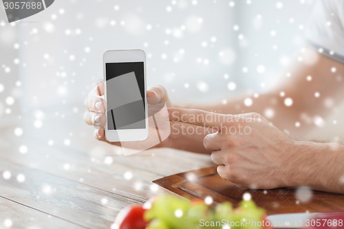 Image of close up of man showing smartphone in kitchen