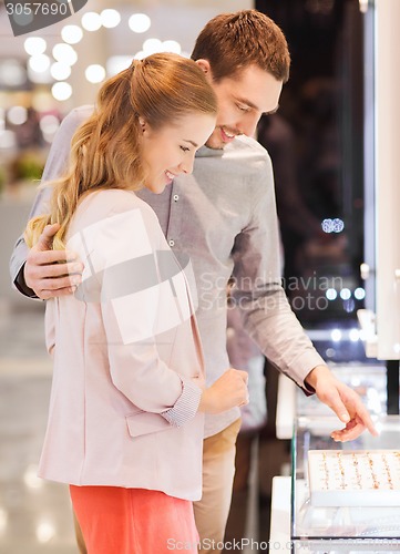 Image of happy couple choosing engagement ring in mall