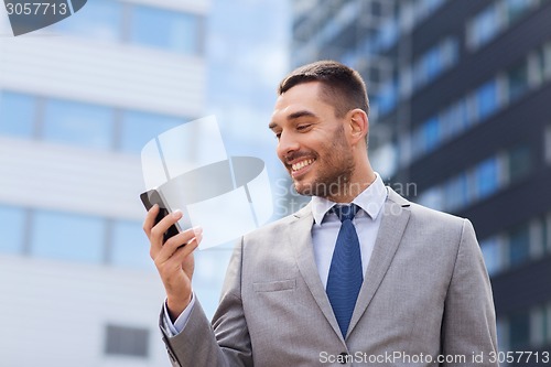 Image of smiling businessman with smartphone outdoors