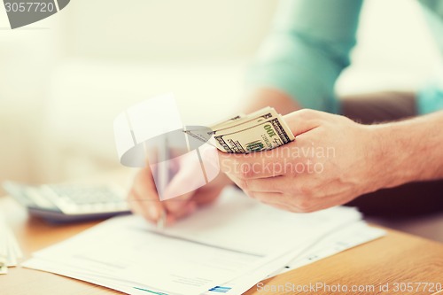 Image of close up of man counting money and making notes