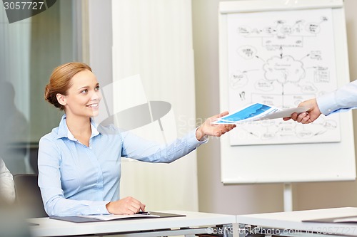 Image of businesswoman taking papers from someone in office