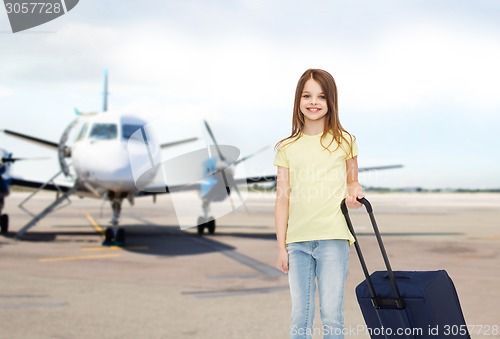 Image of smiling girl with travel bag in airport