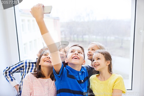 Image of group of school kids taking selfie with smartphone