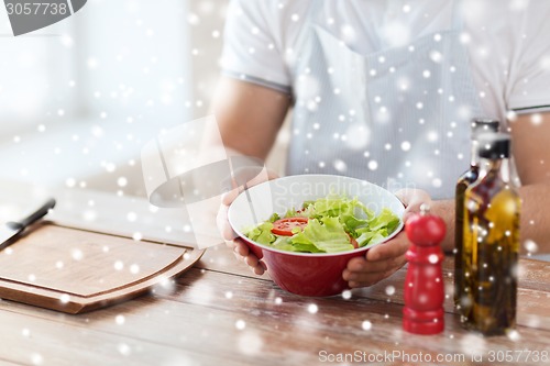 Image of close of male hands holding bowl with salad