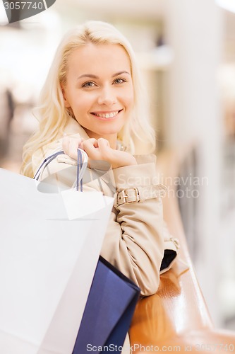 Image of happy young woman with shopping bags in mall