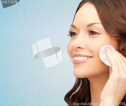 Image of smiling woman cleaning face skin with cotton pad