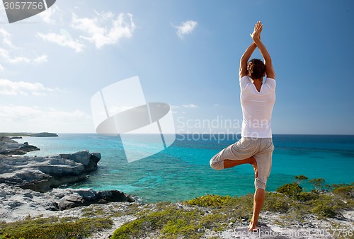 Image of young man making yoga exercises outdoors