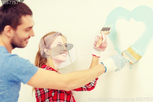 Image of smiling couple painting small heart on wall