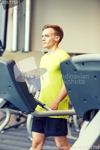 Image of man with smartphone exercising on treadmill in gym