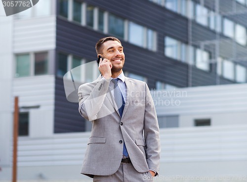 Image of smiling businessman with smartphone outdoors