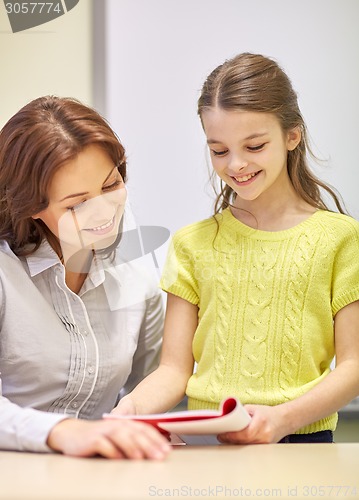 Image of school girl with notebook and teacher in classroom