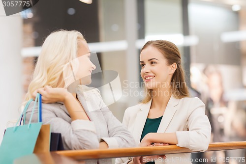 Image of happy young women with shopping bags in mall