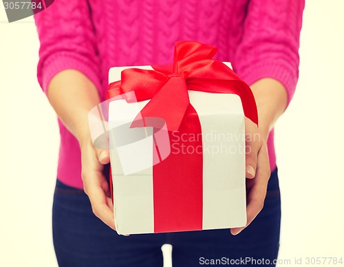 Image of close up of woman in pink sweater holding gift box