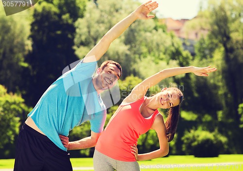 Image of smiling couple stretching outdoors