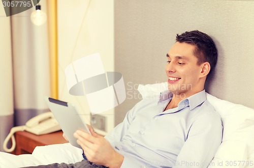 Image of happy businesswoman with tablet pc in hotel room