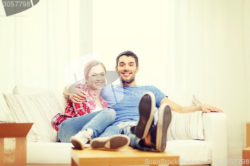 Image of smiling couple relaxing on sofa in new home