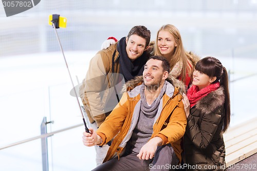 Image of happy friends with smartphone on skating rink