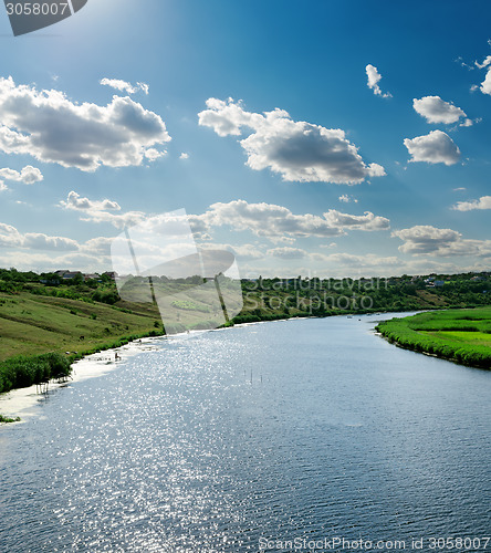 Image of view to river with reflection under blue cloudy sky and sun