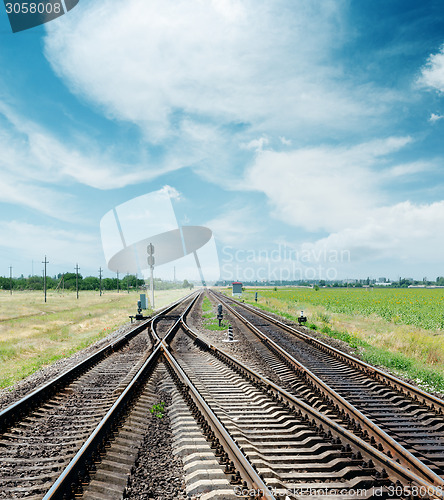 Image of crossing of railroad to horizon under cloudy sky