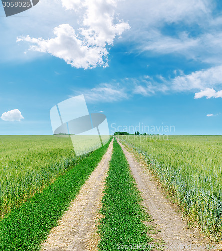 Image of rural road to horizon in green fields and blue sky with clouds