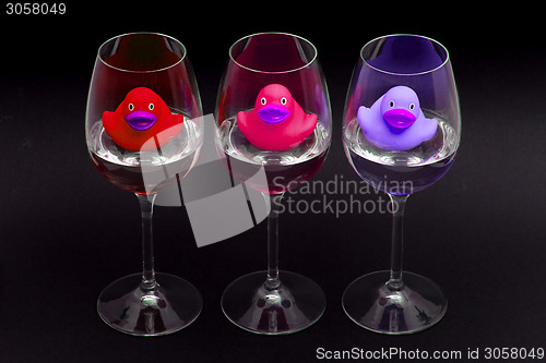 Image of Red, pink and purple rubber ducks in wineglasses